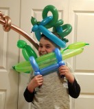 Damian B. poses with multiple balloons at a family event.